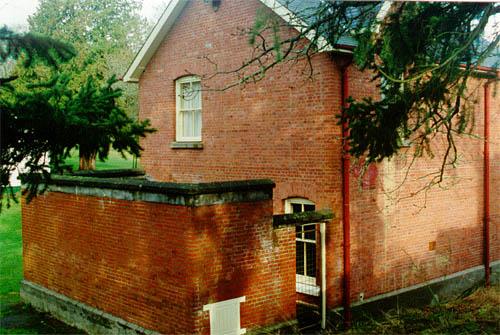 Corner view of the rear of the Warrant Officer's Quarters showing the attached brick enclosure, 1997.; Parks Canada Agency / Agence Parcs Canada, J. Mattie, 1997.