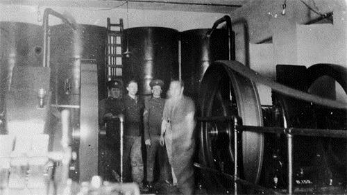 View of the interior of the Searchlight Engine Room demonstrating the remaining interior fittings with two original Hornsby-Ackroyd engines and dynamos, ca. 1930.; Fort Rodd Hill Photo Collection / Collection de photos Rodd Hill, ca. 1930