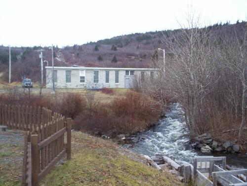 Exterior view of the Victoria Hydro-Electric Station showing the water supply at the front, and the penstock at the rear of the building constructed on the hill behind. Photo taken December 2005.; HFNL/ Dale Jarvis 2005.