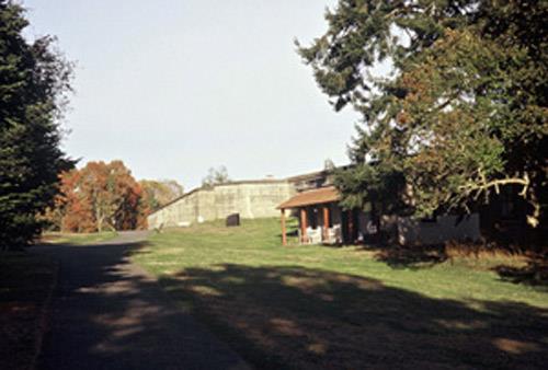 Exterior view of the Fort Rodd Hill Canteen, showing the sloped porch, with its exposed rafters, roof sheathing, and five wood posts with chamfered edges, 2001.; Parks Canada Agency/Agence Parcs Canada, D. Mumford, 2001.