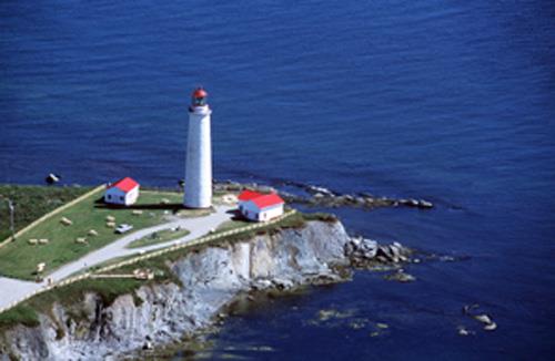 Arial view of the Lighttower at Cap-des-Rosiers putting into evidence its visual prominence owing to its location at the edge of a cliff, its simple, elegant design, massive scale and colour, which all contribute to its soaring, white silhouette, 2001; Parks Canada Agency/Agence Parcs Canada, J.F. Bergeron, 2001.