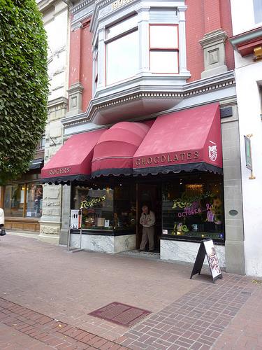 General view of Rogers Building, showing the decorative shopfront including ornate glazing with a delicate canopy of leaded lights over the recessed entrance way, 2011.; Parks Canada Agency / Agence Parcs Canada, Andrew Waldron, 2011.