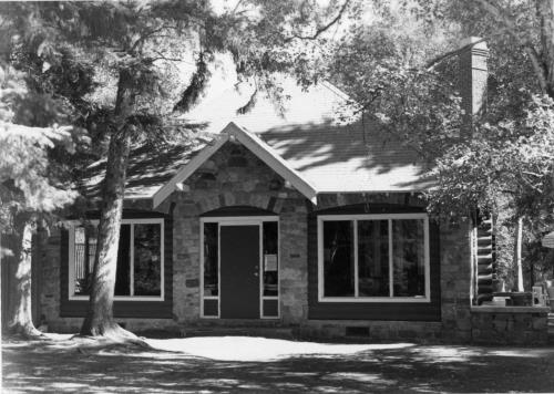 Façade of the Golf Clubhouse, showing the steeply pitched hipped roof with bell-cast eaves, 1986.; Parks Canada Agency / Agence Parcs Canada, Mills, 1986.