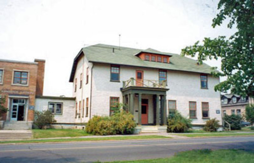 General view of the Dairy Technology Annex, showing the vernacular features and materials of the 1920s building such as the stucco-clad walls, the wooden verandah, wood windows and the shingled, hipped-gable roof.; Department of Agriculture and Agri-Food / Ministère de l'Agriculture et de l'Agroalimentaire, P. Armstrong.