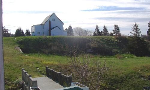 View of the Presentation Convent Grounds, Renews, NL. The bridge in the foreground provided access from the church to the convent and rectory pictured in the background. Photo taken May 2006. ; HFNL/Andrea O'Brien 2006