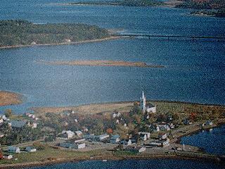 View from the sky, showing the St.Andrew's United Church and cemetery located on a point of land on the Richibucto River.; Village of Rexton