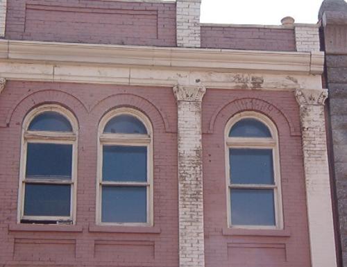 Exterior view of 201 Water Street, close up of masonry details, showing Corinthian Capitals on pilasters, arched windows, recessed panels and boomtown rooftop.  Photo taken July 12, 2006; HFNL/ Deborah O'Rielly 2006
