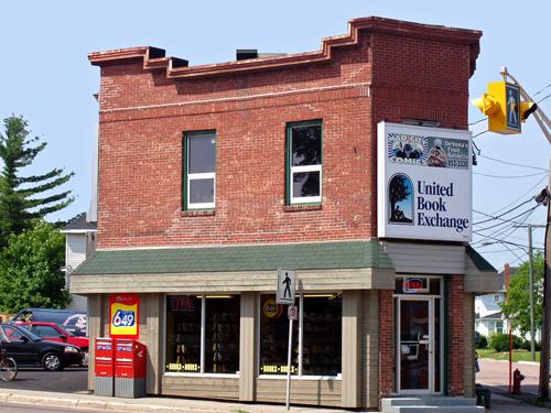 The brick exterior, flat iron shape and distinct parapets have survived since this building was constructed for L. A. Roy in 1922.; Moncton Museum