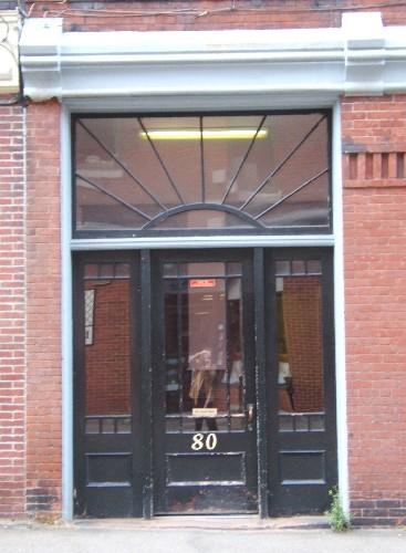 This image provides a view of the entry, with a transom window including fanned muntins over a wood door with a decorative glass panel, surrounded by side-lights, 2005.; City of Saint John