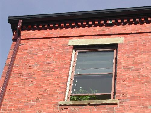 This photograph shows the roof-line cornice with dentils and upper floor window, 2004; City of Saint John
