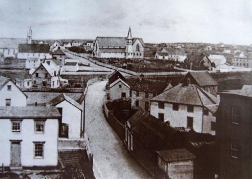 Historic view up Church Street with Christ Church Churchyard Cemetery at corner lot at centre right, with former Christ Church building on its grounds, Bonavista, NL, circa early 1900s; Orville Harris - Bona Photo Media Gallery, Town of Bonavista web site: www.bonavista.net