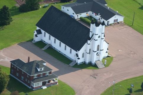 Aerial view of Notre-Dame de l'Annonciation Church with the presbytery in the foreground and the Club d'âge d'or toward the back.; La Société historique de la Valleé de Memramcook et le Village de Memramcook