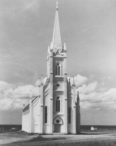 This photo shows the small pinacled spires on the bell tower and the façade, as they originally appeared on the church.; La Société historique de la Valleé de Memramcook