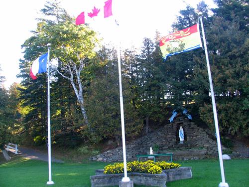 The Grotto and the Calvary - view of the Grotto and the flags.; Village of Saint-Louis-de-Kent