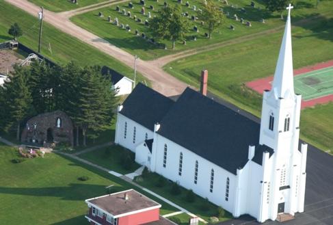 Aerial view showing the placement of the Lourdes Grotto behind the Notre-Dame de Lourdes Church.; La Société historique de la Valleé de Memramcook et le Village de Memramcook