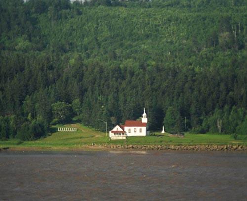 Taken from the opposite side of the Petitcodiac River, this photo shows the Sainte-Anne Chapel, the presbytery and a portion of the cemetery.; La Société historique de la Valleé de Memramcook