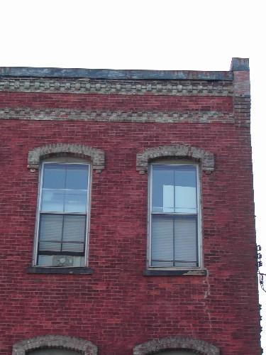 This photograph shows the roof-line and dentils. The ends project above the cornice. Segmented window openings, 2004; City of Saint John