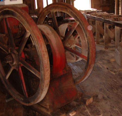 The first engine used in the mill, started by cranking the big fly-wheel and adding gasoline; used for 40 years.  This engine was later replaced by a diesel engine.  Photo taken during Doors Open Placentia event 2006.; HFNL/ 2006