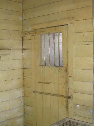 Interior cell door with barred window and hand-wrought hasp, 2004.; Government of Saskatchewan, Marvin Thomas, 2004.