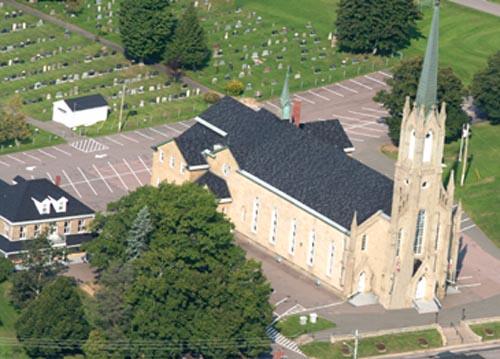 Aerila view of Saint-Thomas de Memramcook Church with the rectory to the left and a portion of the cemetery to the rear; Memramcook Valley Historical Society