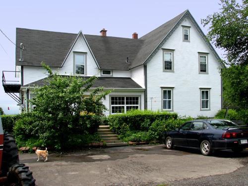 View of east side of farmhouse at 456 Sunset Drive. Gothic Revival influence expressed by bargeboard, steep cross gabled roof and low-pitched veranda roof.; Restigouche Regional Museum, Dalhousie