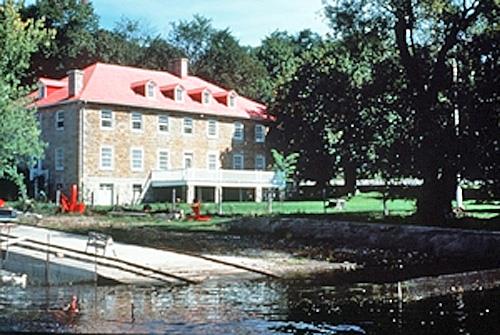 Corner view of the river side of the Carillon Barracks showing the location of the building on the banks of the Ottawa River, next to the Carillon Canal, 1989.; Parks Canada Agency/ Agence Parcs Canada, 1989.