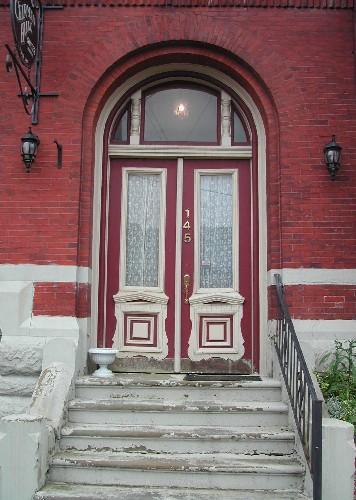 This photograph shows the entryway with the Roman arch transom window and the elaborate, paired wood doors with glass panels, 2005. ; City of Saint John