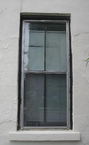 This photograph shows a vertical sliding, two over two wood window with a sandstone sill, 2005.; City of Saint John