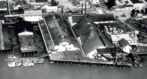 Aerial view of its siting, built on wharf structures out over the river.; Parks Canada Agency / Agence Parcs Canada