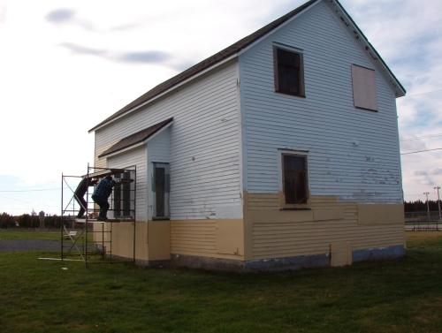 Exterior view of the Bay Roberts Railway Station showing men working on the facade.  They are painting to help protect the exterior until restoration can occur. Photo taken October 17, 2007.; HFNL/ Deborah O'Rielly 2007