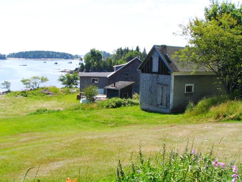 Boat shop buildings with the harbour in the background; Province of New Brunswick