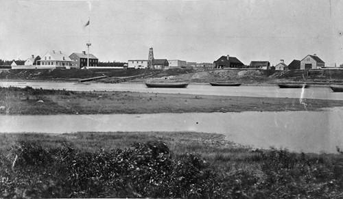 Historic view of Moose Factory showing the HBC Staff House (dark coloured building at left) - 1870; Archives of Canada, 2006