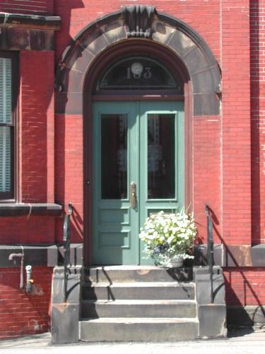 This photograph shows the wooden door and sandstone roman arch entranceway of the residence, 2005; City of Saint John