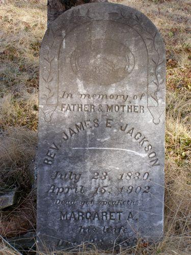 Headstone for Rev. James E. Jackson, an early minister in the community, leaning against a tree in the African Bethel Cemetery, Greenville, Yarmouth, NS, 2008.; Heritage Division, NS Dept. of Tourism, Culture and Heritage, 2008