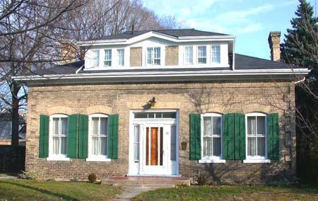 West facing façade featuring the centred dormer, two chimneys, and arch radiating voussiors, 2002.; Department of Planning, City of Brantford, 2002.