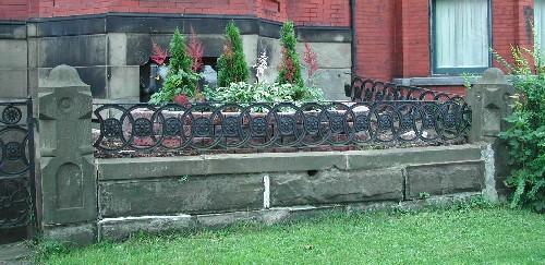This image shows the highly ornate stone and cast iron fence that exhibits a circular and floral design that reflects the pattern specifically designed for the Girl Guide cookies, 2005.; City of Saint John