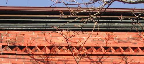 This image shows the wooden cornice with a decorative band of brickwork below, 2005.; City of Saint John