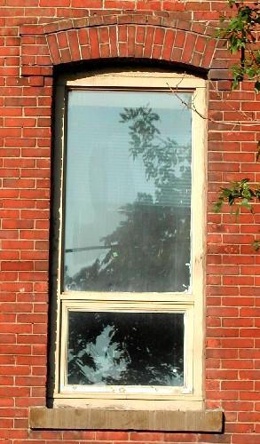 This image provides a view of a segmented arched window opening below a brick hood mould ending in corbel stops, 2005.; City of Saint John