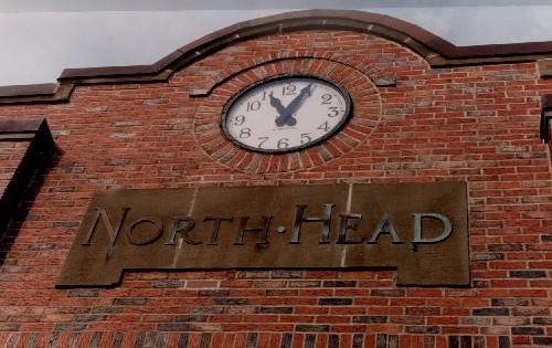 Detail view of the Government of Canada Building in North Head, showing a semi-circular parapet wall which frames a round clock, 1993.; Public Works and Government Services Canada / Travaux publics et Services gouvernementaux Canada, 1993.
