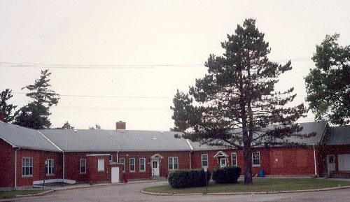 Rear view of Building A-74 (Maple Mess), showing its brick cladding and multi-paned window treatments in their varying configurations, 1992.; Department of National Defence / Ministère de la Défense nationale, 1992.