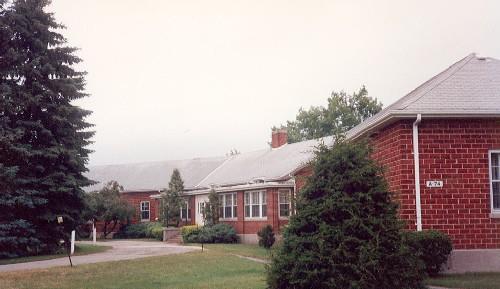 Corner view of Building A-74 (Maple Mess), showing its roof profiles and chimneys and the details of the main entrance, 1992.; Department of National Defence / Ministère de la Défense nationale, 1992.