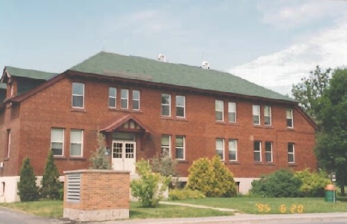 View of the main entrance to the Arc Biotech Building (No. 34); showing the ornamental eave dentils, the entrance topped by a transom window and the projecting pediment with mock half-timbering, 1999.; Agence Parcs Canada / Parks Canada Agency, 1999.