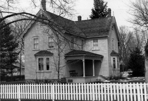 View of the south façade of Bethune House, showing the clapboard exterior walls, the symmetrical arrangement of the windows, the bay windows and the verandah, 1989.; Agence Parcs Canada / Parks Canada Agency, 1989.