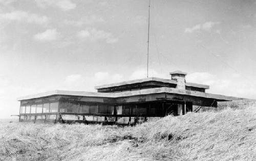 Corner view of the Battery Command Post, showing the main façade and the simple massing of the structure that is partially concealed within the central mound, ca. 1945.; Department of National Defence / Ministère de la Défense nationale, ca. 1945.