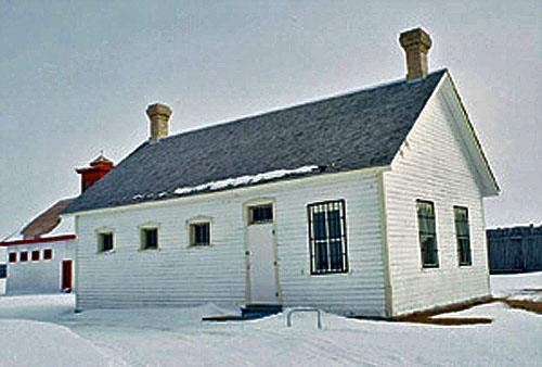 General view of the Guard House, showing the spacing of the door and window openings, the multi-paned windows and the steel bars over some of the windows, 1991.; Agence Parcs Canada / Parks Canada Agency, D. McArthur, 1991.