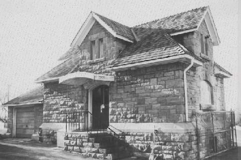 View of the Maintenance Building's main entrance, showing the stone front porch with iron siding and the semi-elliptical window, 1988.; National Capital Commission / Commission de la capitale nationale, 1988.
